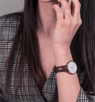 Person wearing a brown wristwatch with a plaid shirt